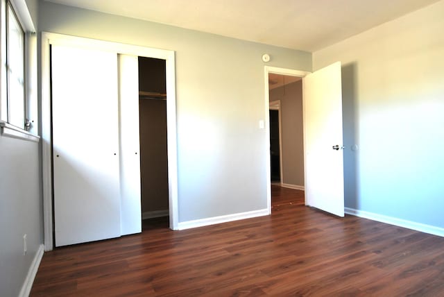 unfurnished bedroom with dark hardwood / wood-style floors and a closet