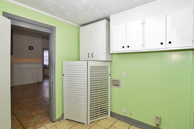 laundry area with light tile patterned flooring, cabinets, and a textured ceiling