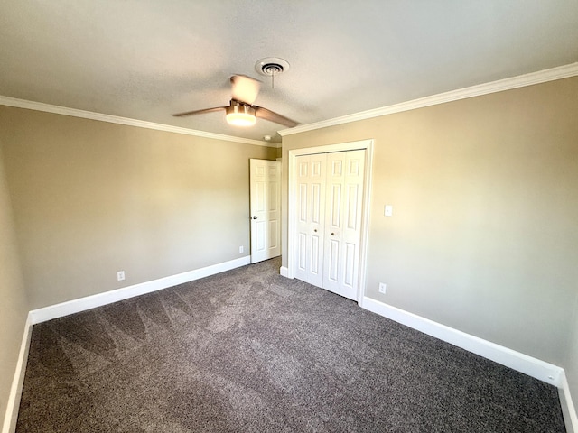 unfurnished bedroom featuring a closet, baseboards, ceiling fan, dark colored carpet, and ornamental molding