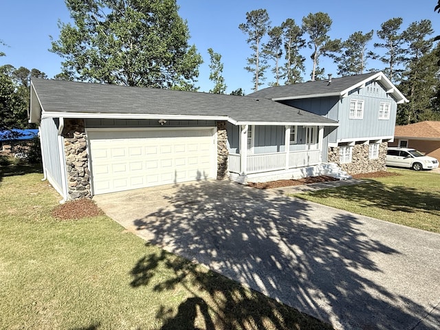 split level home with covered porch, stone siding, concrete driveway, a front yard, and board and batten siding