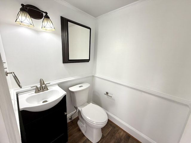 half bathroom featuring toilet, wood finished floors, vanity, ornamental molding, and baseboards