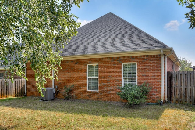 view of side of property with a lawn and central AC