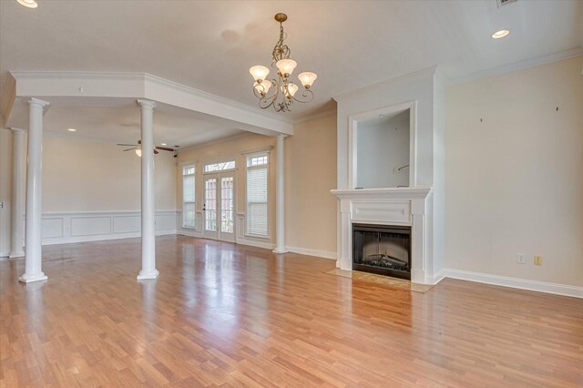 unfurnished living room with ceiling fan with notable chandelier, light hardwood / wood-style floors, and crown molding