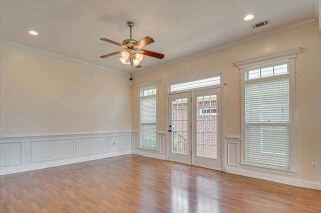 spare room featuring a healthy amount of sunlight, light hardwood / wood-style flooring, ceiling fan, and ornamental molding