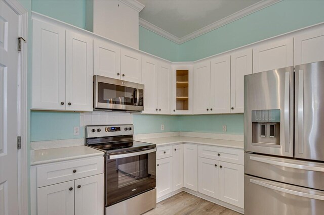 kitchen featuring light hardwood / wood-style flooring, white cabinetry, stainless steel appliances, and ornamental molding