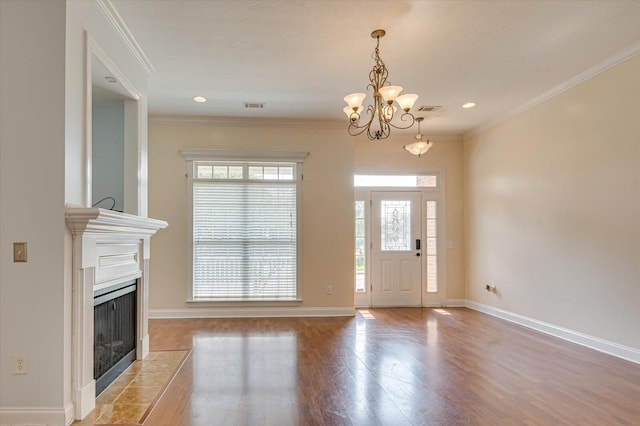 unfurnished living room featuring a notable chandelier, crown molding, a fireplace, and a wealth of natural light