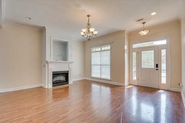 foyer featuring wood-type flooring, crown molding, and a chandelier