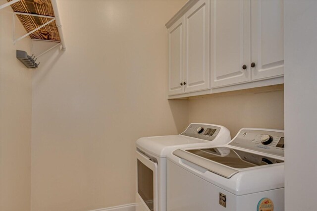 clothes washing area with washer and dryer and cabinets