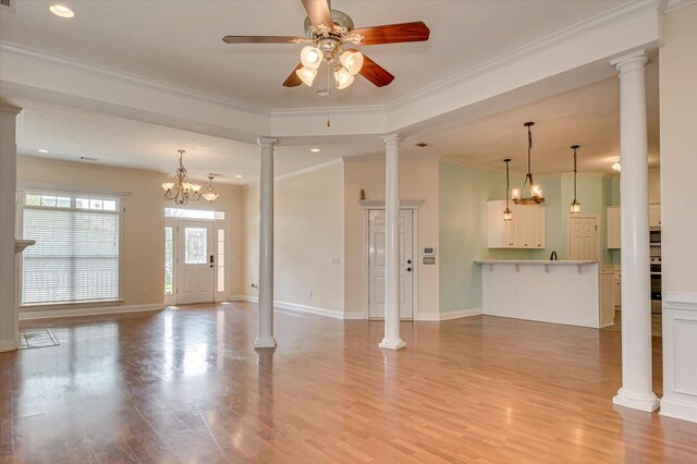 unfurnished living room with ceiling fan with notable chandelier, light hardwood / wood-style flooring, and ornamental molding