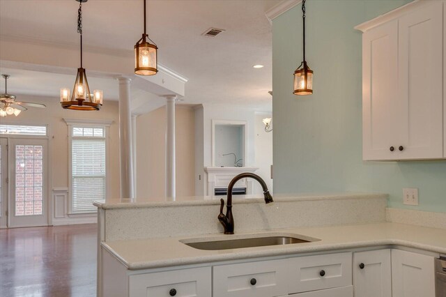 kitchen with ceiling fan, sink, hanging light fixtures, decorative columns, and white cabinets