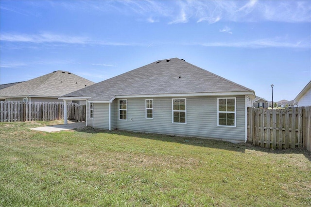rear view of property featuring a yard, a fenced backyard, and roof with shingles