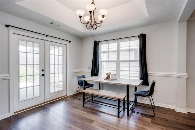 dining area featuring visible vents, wood finished floors, a raised ceiling, a chandelier, and french doors