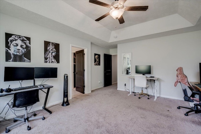 office space with baseboards, carpet, a raised ceiling, and a ceiling fan
