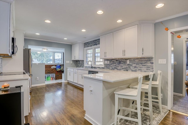 kitchen with a breakfast bar, white cabinetry, crown molding, and dark wood-type flooring