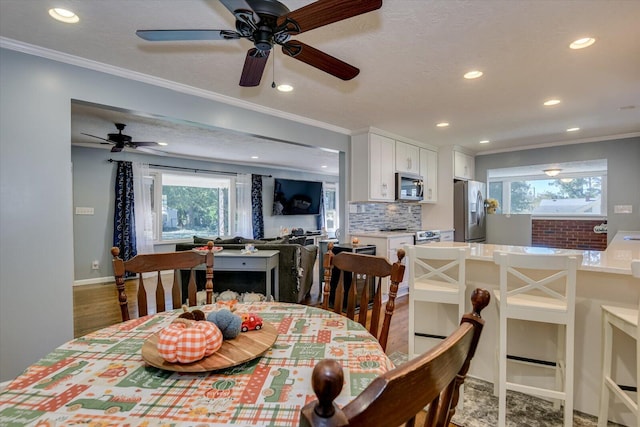 dining space with hardwood / wood-style flooring, ceiling fan, crown molding, and a textured ceiling