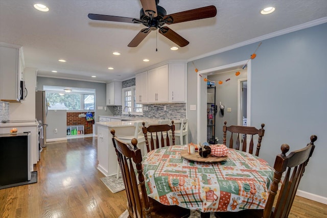 dining space with ceiling fan, crown molding, light wood-type flooring, and sink