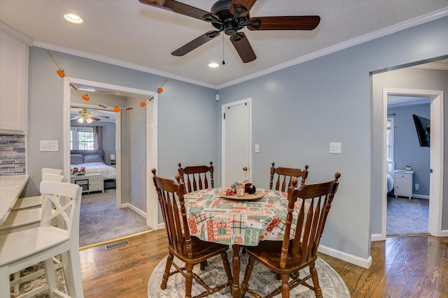 dining area featuring hardwood / wood-style flooring, ceiling fan, and crown molding