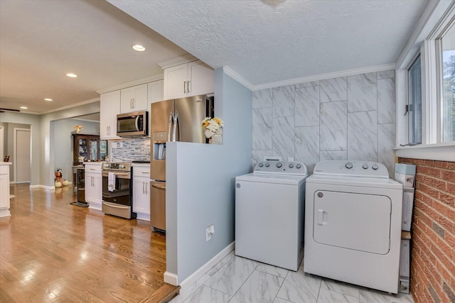 clothes washing area featuring a textured ceiling, washer and clothes dryer, and ornamental molding