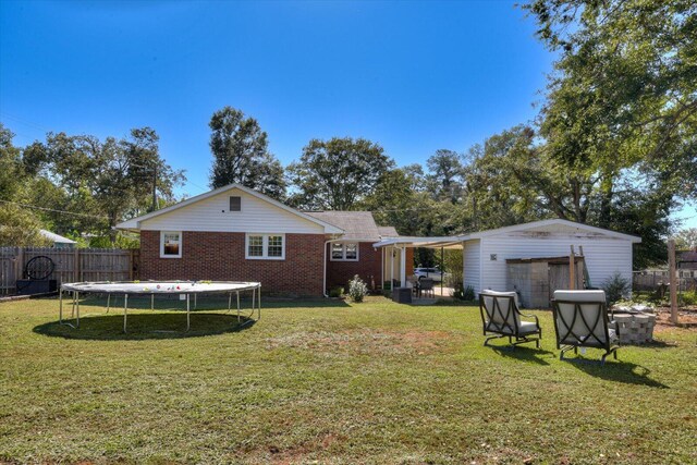 back of property featuring a lawn and a trampoline