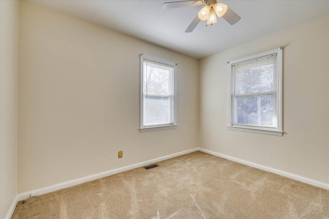 empty room with a wealth of natural light, carpet flooring, visible vents, and baseboards