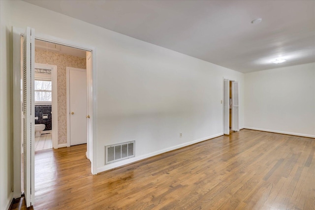 unfurnished room featuring wood finished floors, visible vents, and baseboards