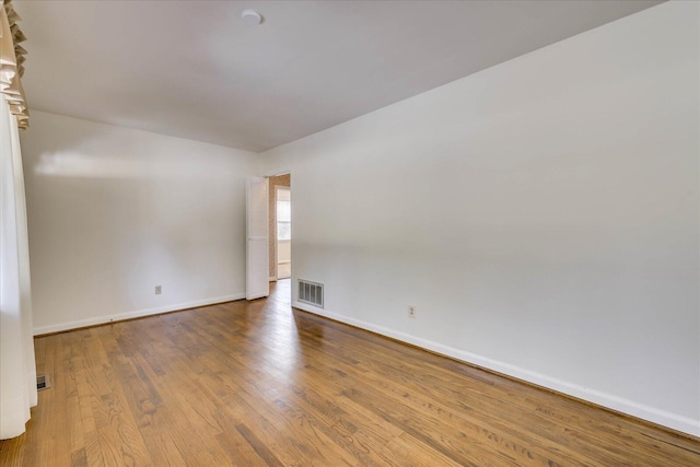 unfurnished room featuring baseboards, visible vents, and wood finished floors