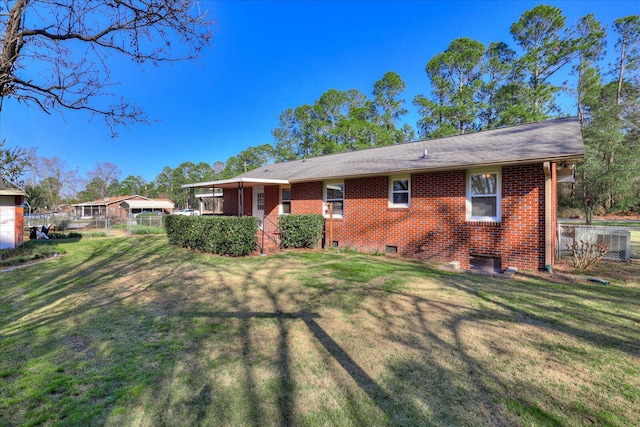 back of house featuring crawl space, brick siding, a lawn, and fence