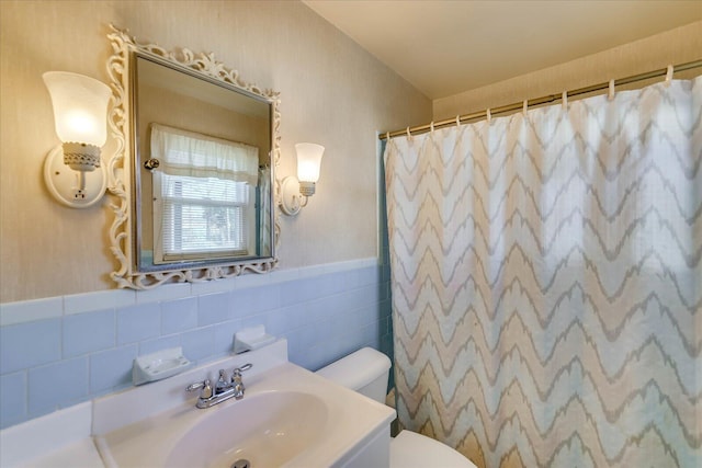 full bathroom featuring wainscoting, toilet, curtained shower, vanity, and tile walls