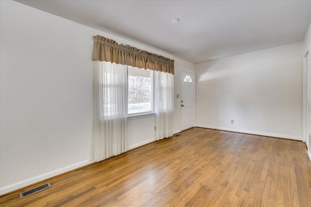 empty room with visible vents, baseboards, and wood finished floors