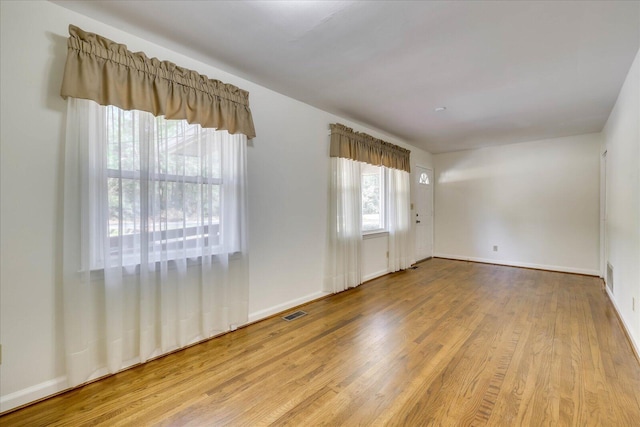 spare room with visible vents, baseboards, and wood finished floors