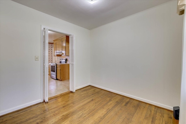 spare room featuring baseboards and light wood-style floors