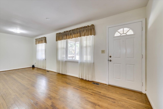 foyer entrance featuring baseboards, visible vents, and wood finished floors