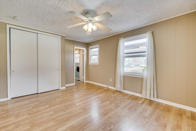 unfurnished bedroom with a textured ceiling, ceiling fan, a closet, and wood finished floors