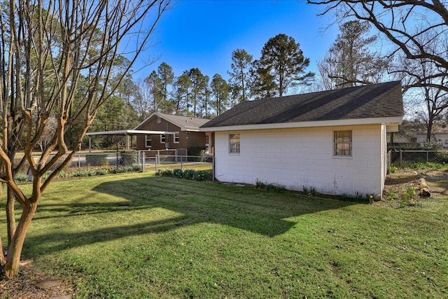 exterior space with a shingled roof, fence, concrete block siding, and a yard