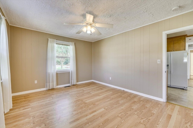 empty room with a textured ceiling, a ceiling fan, visible vents, light wood-type flooring, and crown molding