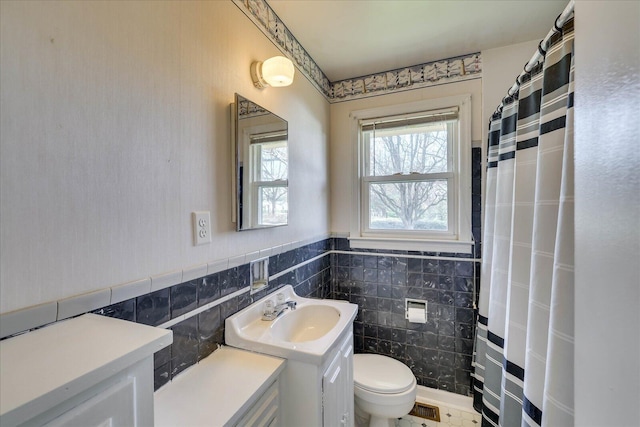 full bathroom with toilet, a wainscoted wall, a shower with curtain, and tile walls