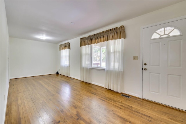 foyer entrance with visible vents, baseboards, and wood finished floors