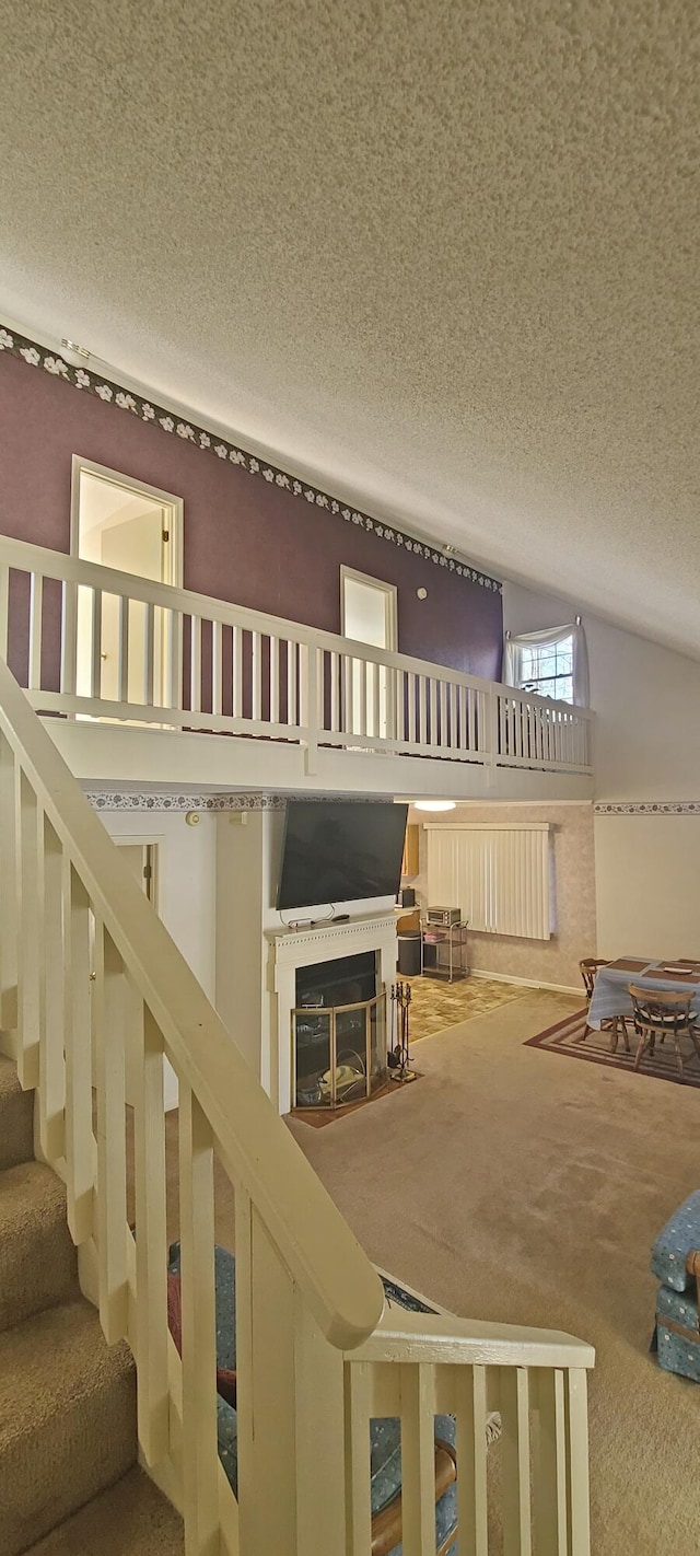 carpeted living area featuring a textured ceiling, stairs, and lofted ceiling