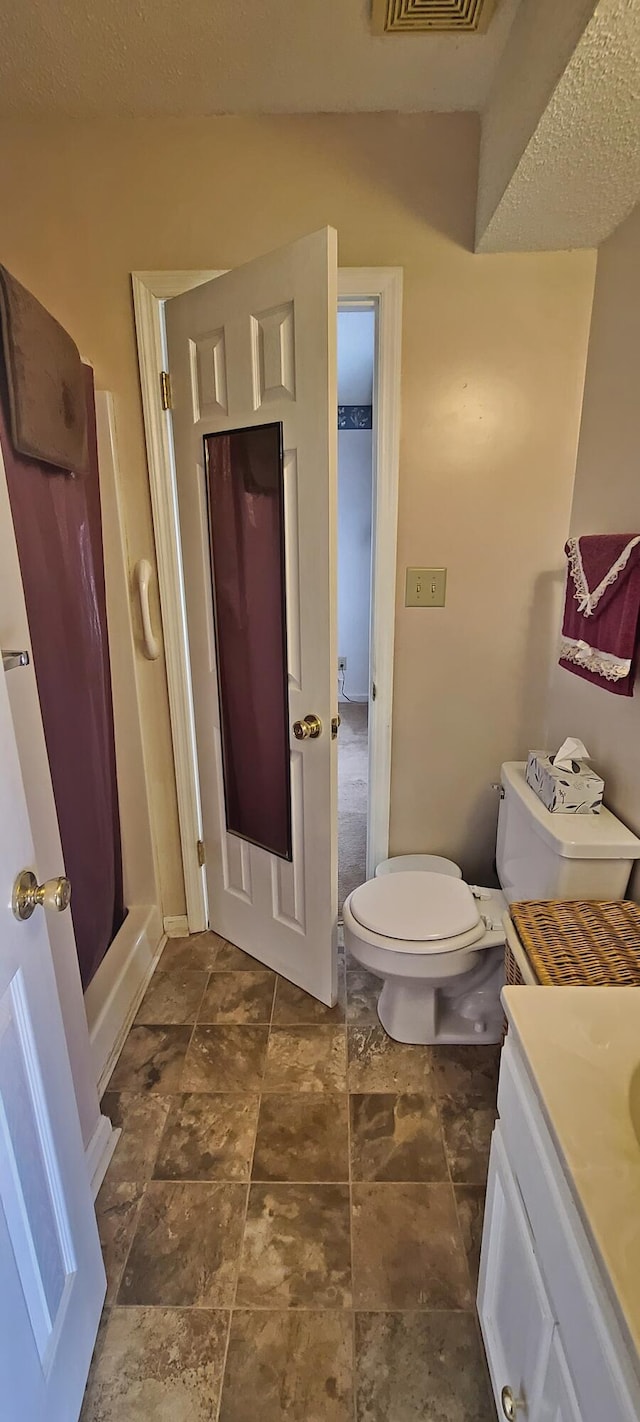 bathroom with vanity, toilet, visible vents, and walk in shower