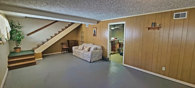 below grade area with visible vents, stairway, wood walls, ornamental molding, and a textured ceiling