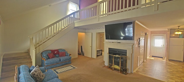 carpeted living room with a fireplace with flush hearth, plenty of natural light, a high ceiling, and stairs