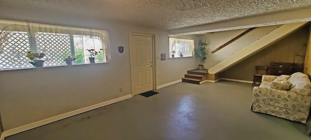 entryway featuring stairway, a textured ceiling, concrete flooring, and baseboards