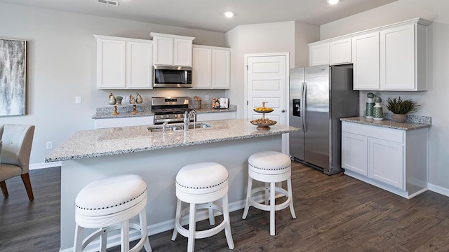 1255 Birch Cir, Grovetown, GA 30813 - kitchen with appliances with stainless steel finishes, white cabinetry, dark wood finished floors, a center island with sink, and a breakfast bar