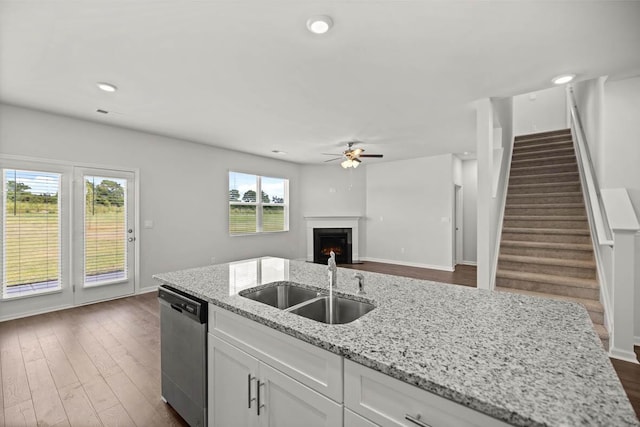 1255 Birch Cir, Grovetown, GA 30813 - kitchen with stainless steel dishwasher, a sink, ceiling fan, white cabinets, and a lit fireplace