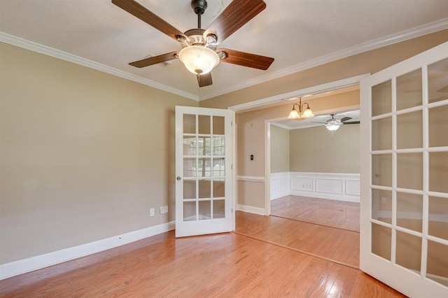 spare room featuring hardwood / wood-style flooring, an inviting chandelier, ornamental molding, and french doors