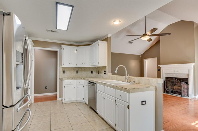 kitchen featuring kitchen peninsula, stainless steel appliances, ceiling fan, sink, and white cabinets