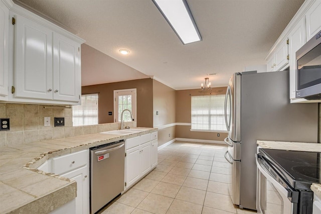 kitchen featuring sink, light tile patterned floors, plenty of natural light, white cabinetry, and stainless steel appliances