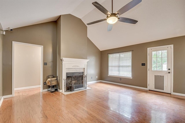 unfurnished living room featuring ceiling fan, light wood-type flooring, lofted ceiling, and a tiled fireplace