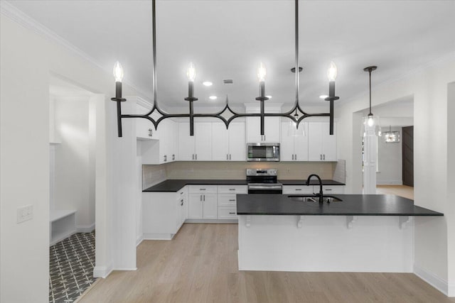 kitchen with pendant lighting, backsplash, sink, appliances with stainless steel finishes, and white cabinetry