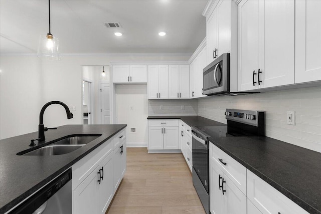 kitchen with sink, white cabinets, stainless steel appliances, and decorative light fixtures